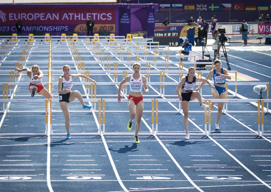 ランニングトラックで時計を確認しながら練習ペースを調整するランナー